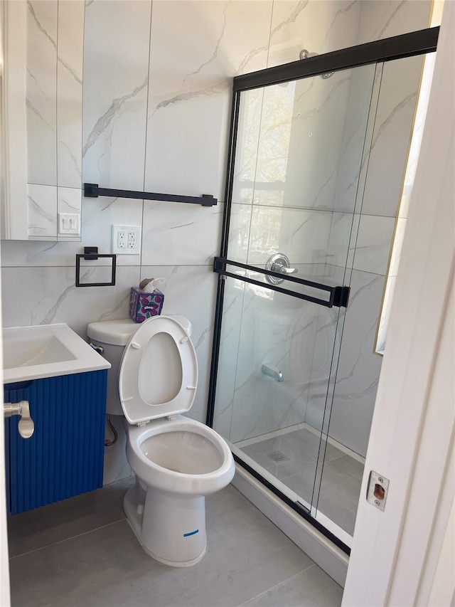 bathroom with a stall shower, toilet, vanity, and tile walls