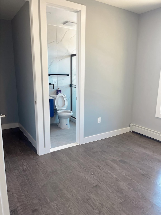unfurnished bedroom with dark wood-style flooring, baseboards, and ensuite bath