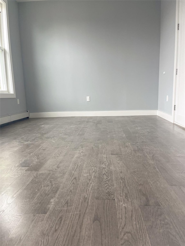 spare room with a baseboard radiator, baseboards, and wood finished floors