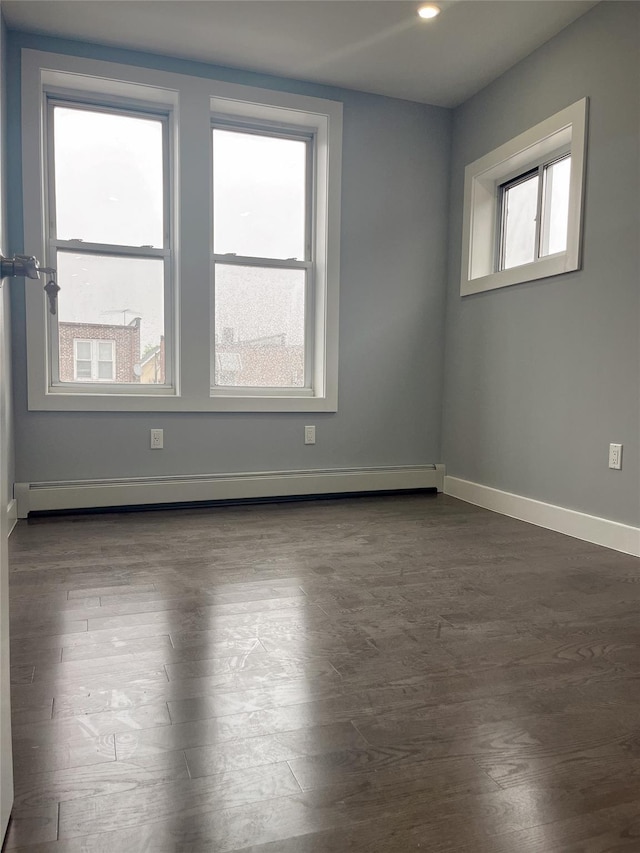 spare room with plenty of natural light, dark wood finished floors, baseboards, baseboard heating, and recessed lighting