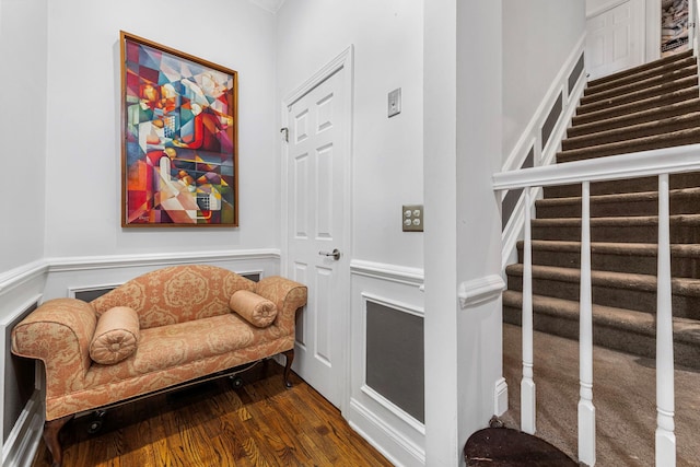 living area featuring stairway, dark wood-style floors, and wainscoting