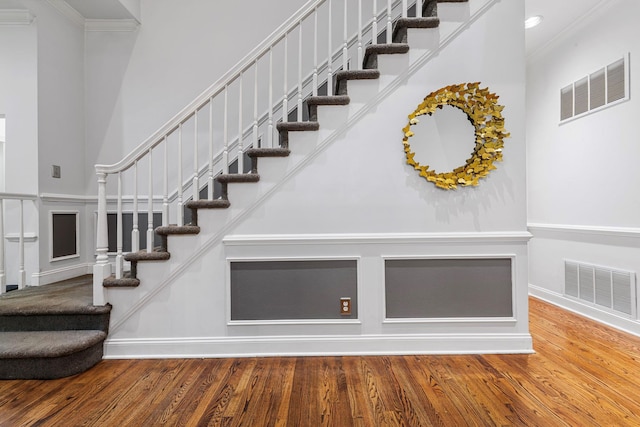 stairway with wood finished floors, ornamental molding, baseboards, and recessed lighting