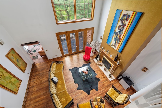 living room with a high ceiling, wood finished floors, french doors, and baseboards