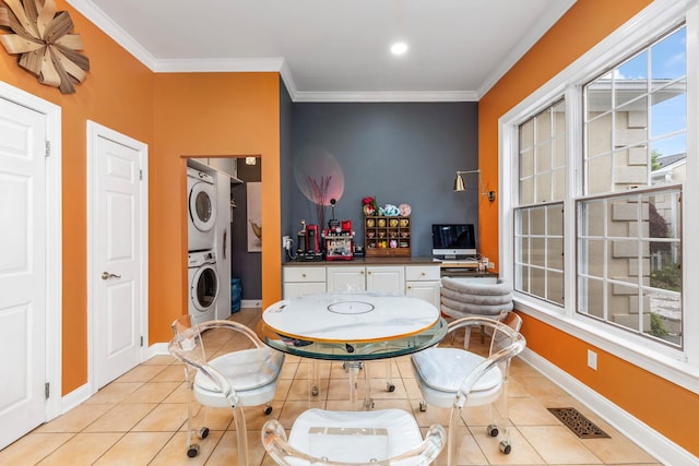 dining space with stacked washer / dryer, crown molding, light tile patterned flooring, and baseboards