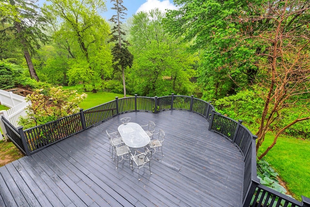 wooden terrace featuring outdoor dining space and a yard