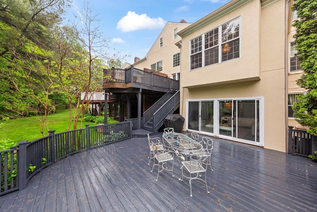 wooden terrace featuring stairs, a yard, and outdoor dining space