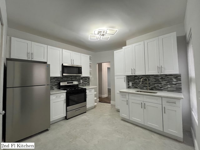 563 E 3rd St, Mount Vernon, NY 10553 - kitchen with appliances with stainless steel finishes, a sink, light countertops, decorative backsplash, and white cabinets