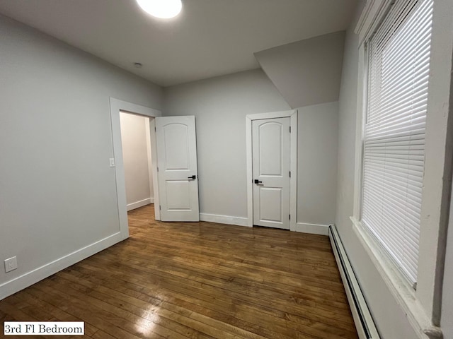 563 E 3rd St, Mount Vernon, NY 10553 - unfurnished bedroom featuring dark wood-type flooring, baseboards, and a baseboard heating unit