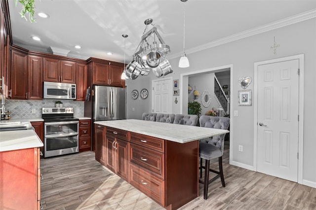 25 Crest Rd, Cold Spring, NY 10516 - kitchen featuring stainless steel appliances, crown molding, a kitchen breakfast bar, light countertops, and light wood-type flooring