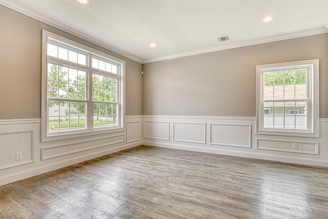 unfurnished room featuring ornamental molding, plenty of natural light, a wainscoted wall, wood finished floors, and recessed lighting