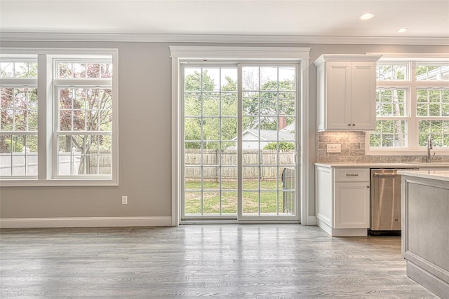 entryway featuring crown molding, light wood-style flooring, baseboards, and a sink