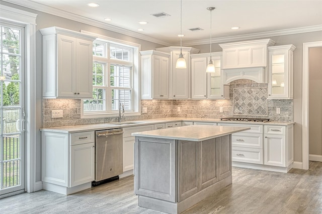 kitchen with appliances with stainless steel finishes, a sink, light wood-style flooring, white cabinets, and ornamental molding