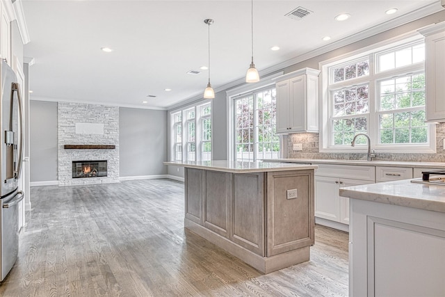kitchen with a sink, crown molding, light wood-type flooring, decorative backsplash, and recessed lighting