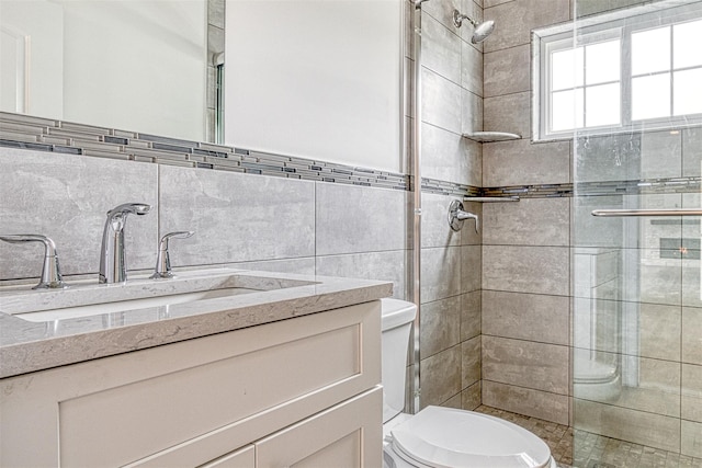 full bath with a shower stall, toilet, vanity, and tile walls