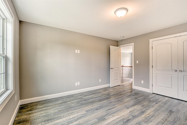 unfurnished bedroom with wood finished floors, baseboards, and a closet