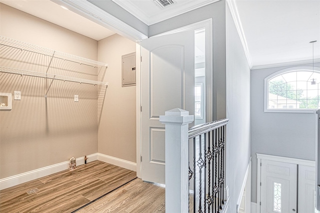laundry room featuring ornamental molding, light wood-style flooring, electric panel, and baseboards