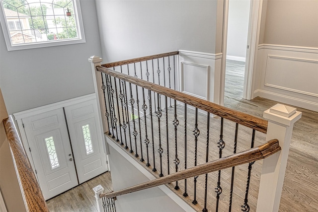 stairway featuring a decorative wall, wood finished floors, and a wainscoted wall