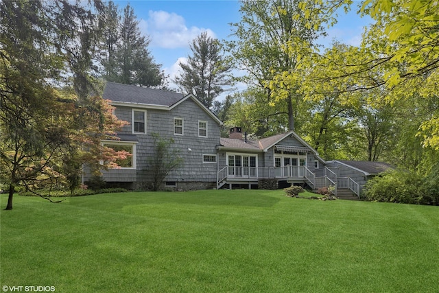 rear view of property featuring a wooden deck, a yard, and a chimney