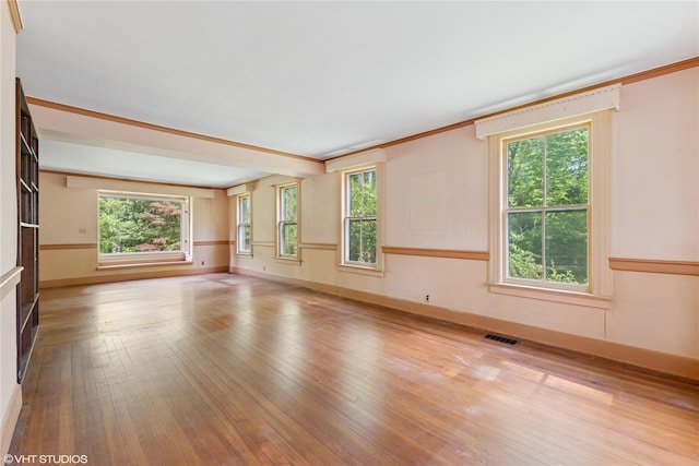 spare room featuring healthy amount of natural light, wood-type flooring, and baseboards