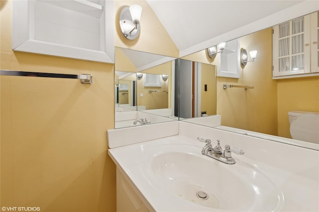 half bathroom with vanity, toilet, and lofted ceiling