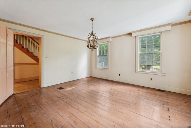 unfurnished room featuring plenty of natural light, a chandelier, wood-type flooring, stairway, and ornamental molding
