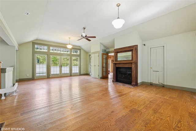 unfurnished living room with vaulted ceiling, a fireplace with flush hearth, light wood-style flooring, a ceiling fan, and baseboards