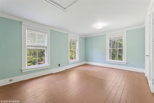 unfurnished room with baseboards, hardwood / wood-style flooring, ornamental molding, and healthy amount of natural light