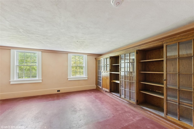unfurnished room with baseboards and a textured ceiling