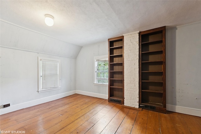 unfurnished bedroom featuring wood-type flooring, baseboards, lofted ceiling, and a textured ceiling