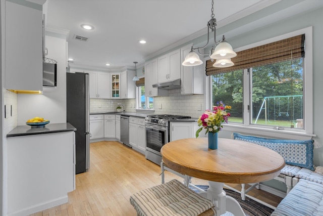 411 8th Ave, East Northport, NY 11731 - kitchen featuring appliances with stainless steel finishes, under cabinet range hood, dark countertops, white cabinets, and backsplash