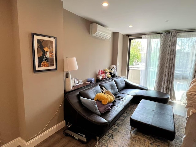 living area with an AC wall unit, wood finished floors, baseboards, and recessed lighting
