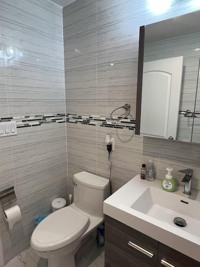 bathroom with tile walls, toilet, vanity, and decorative backsplash
