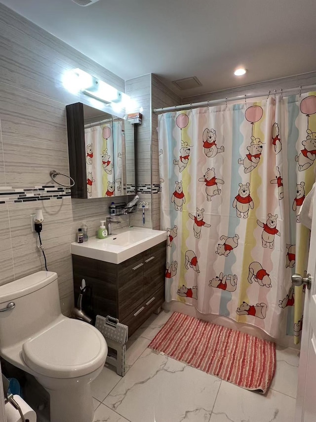 full bathroom featuring marble look tile flooring, vanity, toilet, a shower with curtain, and tile walls