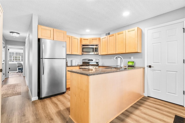 1 Mountain Ter, Nanuet, NY 10954 - kitchen featuring appliances with stainless steel finishes, light brown cabinetry, a peninsula, a textured ceiling, and light wood-type flooring