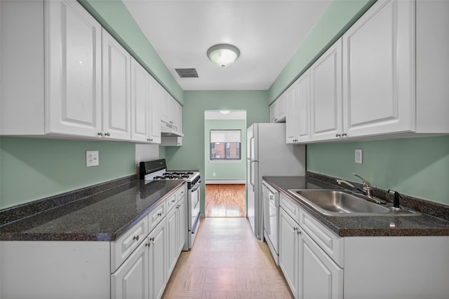 kitchen with gas stove, under cabinet range hood, a sink, white cabinetry, and dark countertops