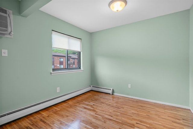 unfurnished room featuring a baseboard heating unit, wood finished floors, and baseboards