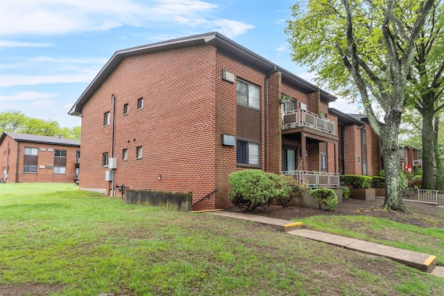 view of side of home with a lawn, brick siding, and a balcony