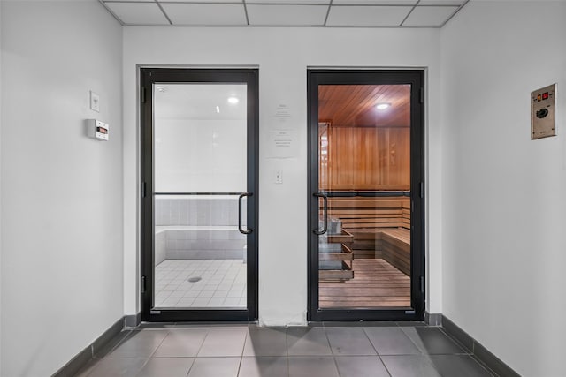 entryway featuring tile patterned floors, baseboards, a paneled ceiling, and a relaxing sauna