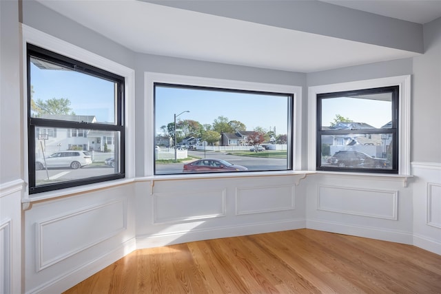 spare room with light wood finished floors, wainscoting, and a decorative wall