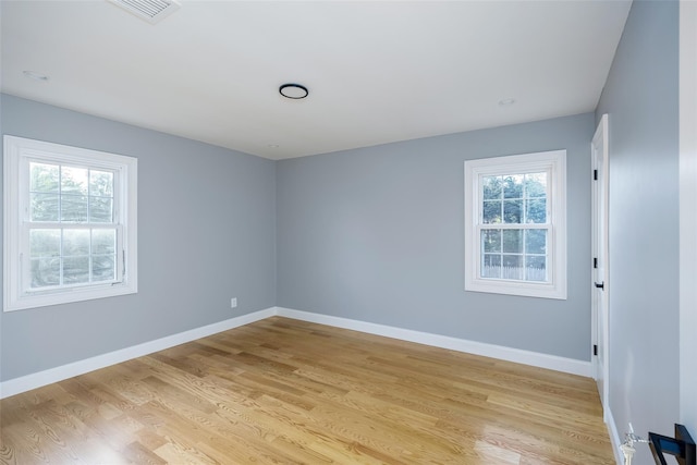 spare room featuring healthy amount of natural light, light wood finished floors, and baseboards