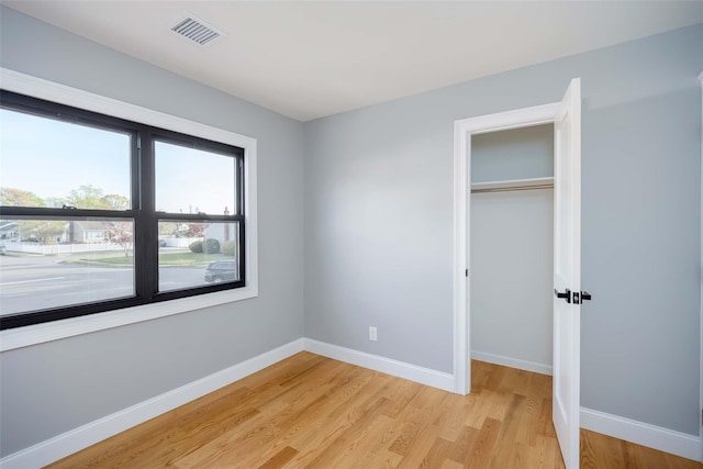 unfurnished bedroom featuring light wood-type flooring, baseboards, and a closet