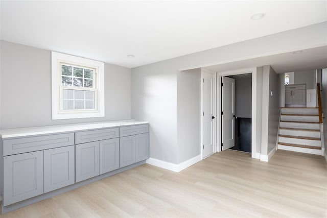 unfurnished room with light wood-style floors, baseboards, and stairway