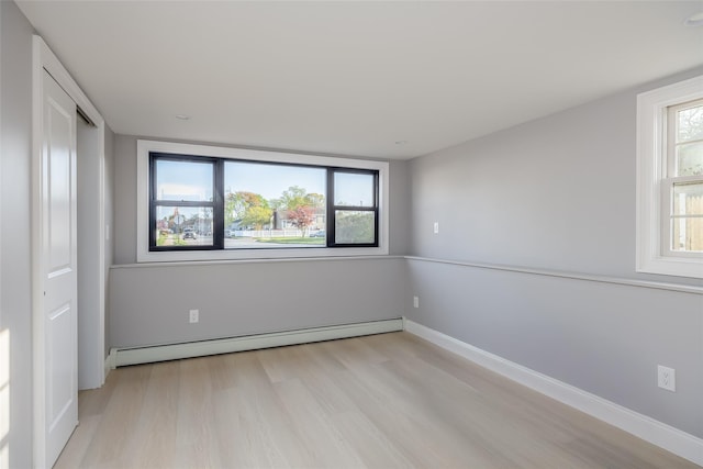 empty room with light wood-style floors, baseboard heating, and baseboards
