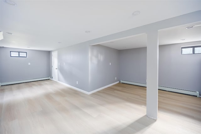 basement featuring baseboard heating, light wood finished floors, and baseboards