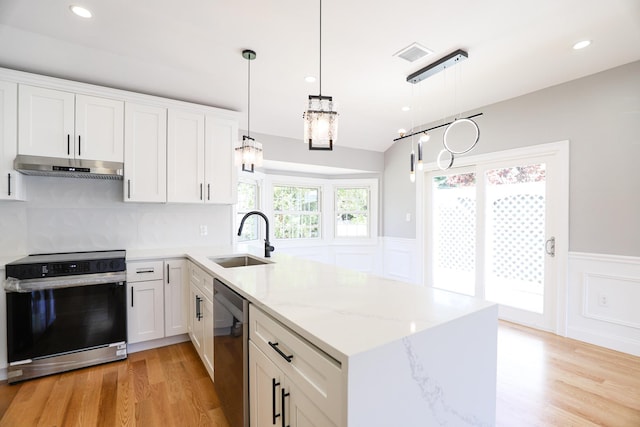 kitchen with a sink, electric range oven, under cabinet range hood, dishwasher, and a peninsula