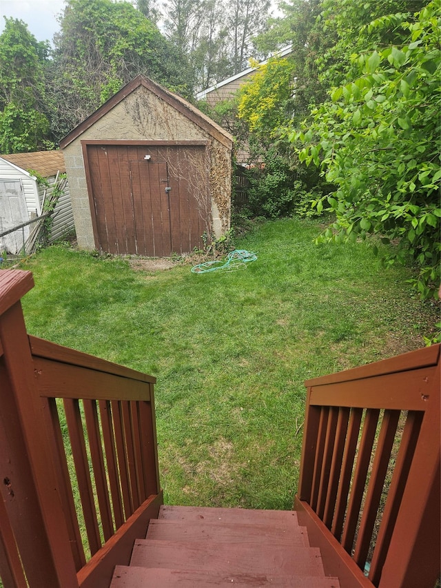 view of green lawn with a storage unit and an outbuilding