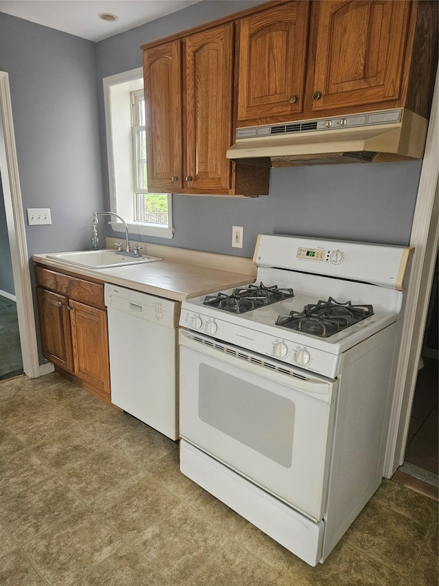 kitchen featuring white appliances, a sink, under cabinet range hood, and brown cabinets