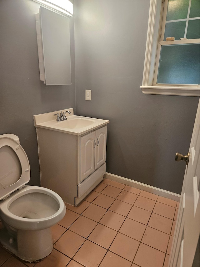 half bath featuring tile patterned flooring, toilet, vanity, and baseboards