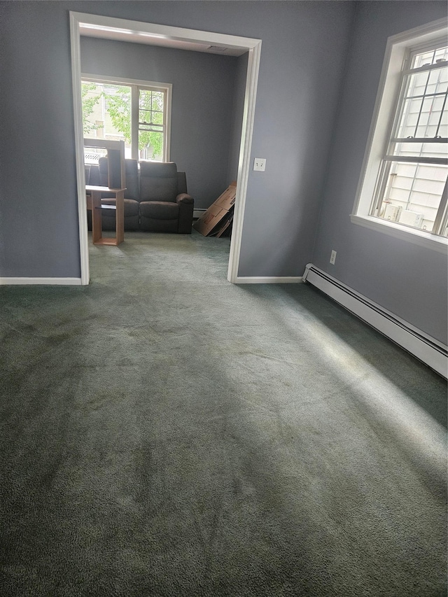 carpeted spare room with baseboards and a baseboard heating unit