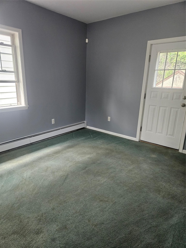 empty room with a baseboard heating unit, dark carpet, and baseboards
